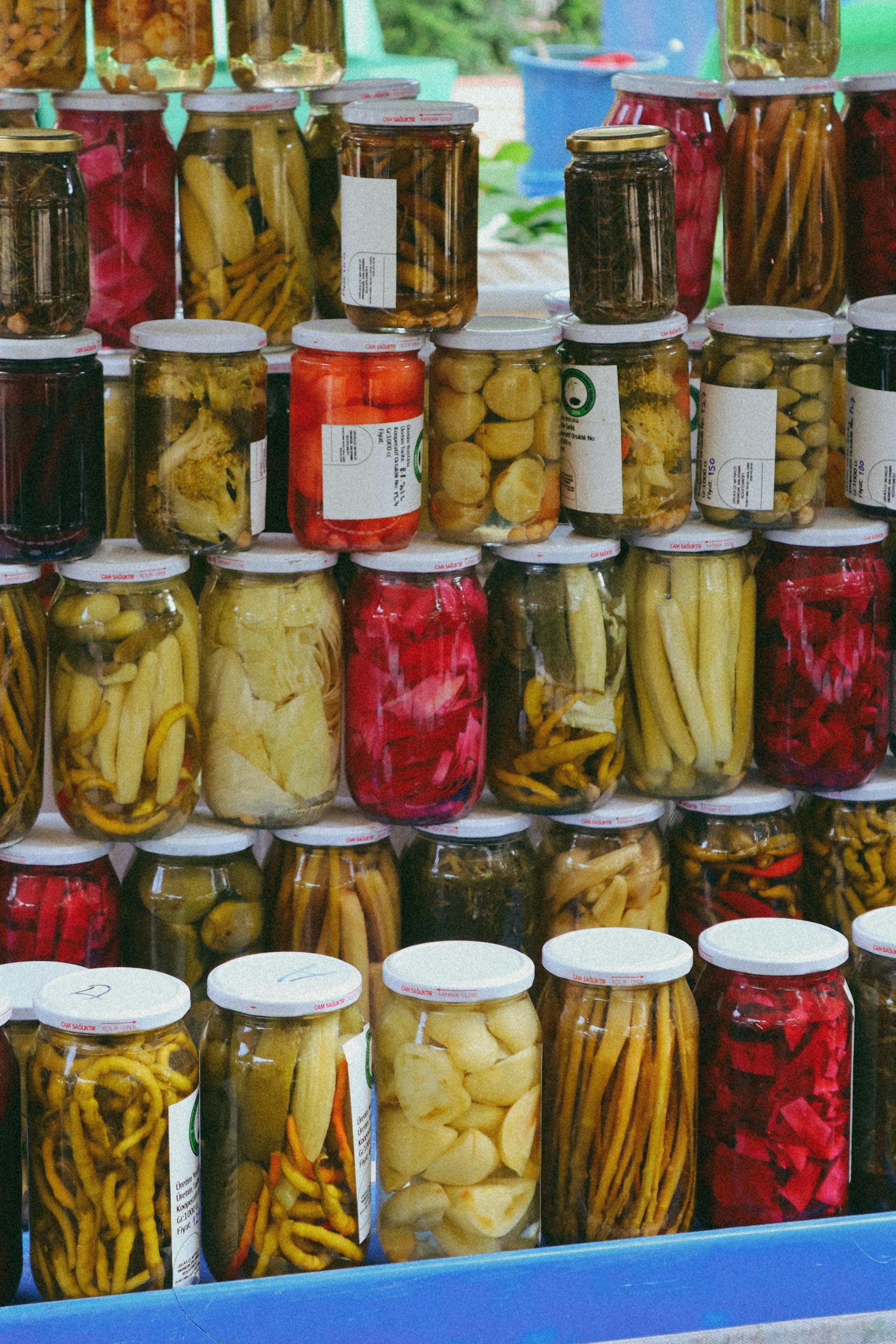 Vibrant display of pickled vegetables in jars at a traditional Turkish market.