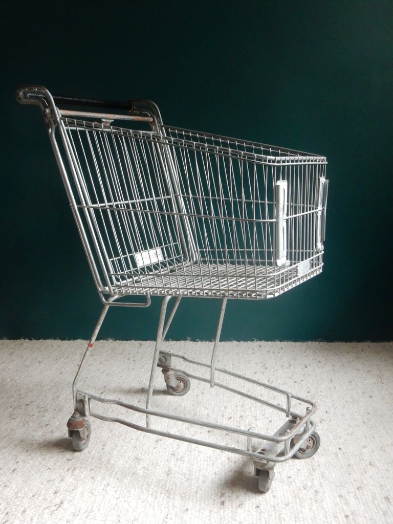 A minimalist shot of an industrial shopping cart against a dark backdrop.