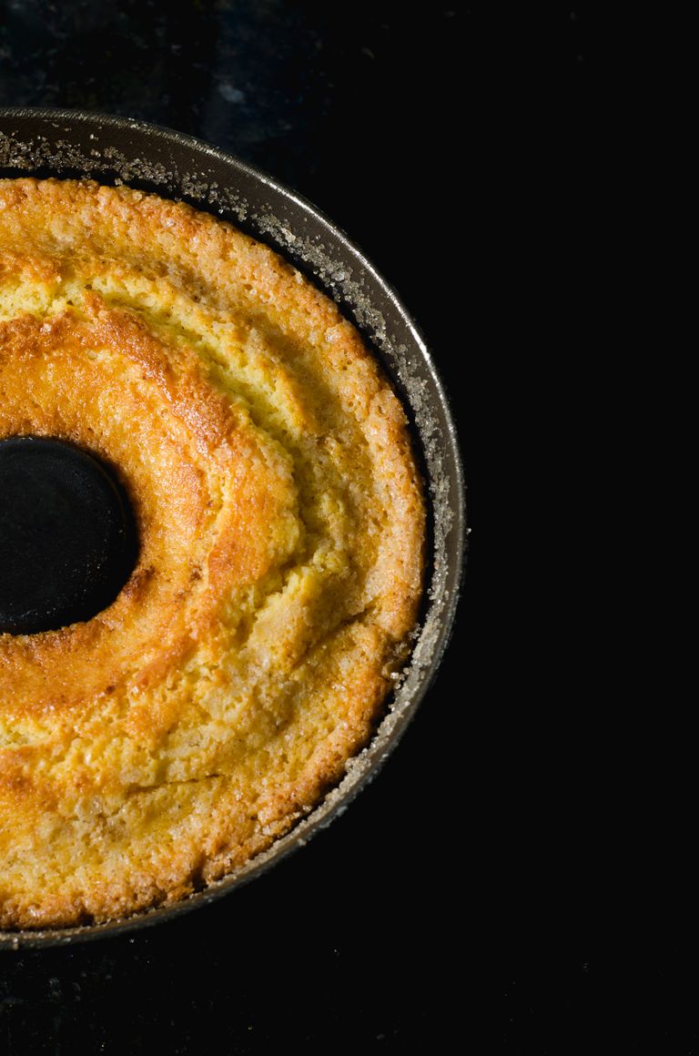 Close-up of a delicious homemade bundt cake with a golden crust against a dark background.
